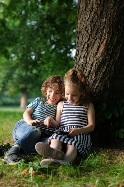 The boy and the girl of 7-8 years smiling look in the tablet.