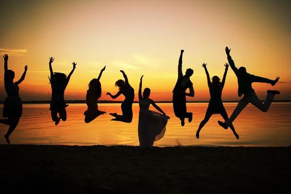 Silhouettes of group people in a jump at sunset.