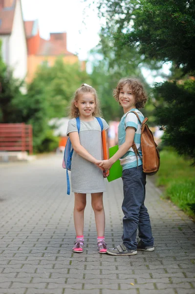 Two pupils, boy and girl, on the way to school.