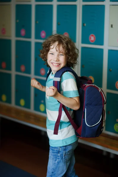 The schoolboy standing near lockers in school hallway.