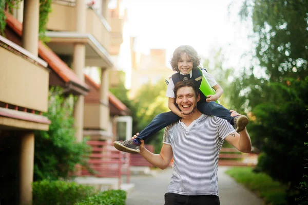 The father carries the son to school on shoulders