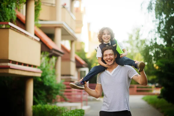 The father carries on shoulders of his son-schooboy.