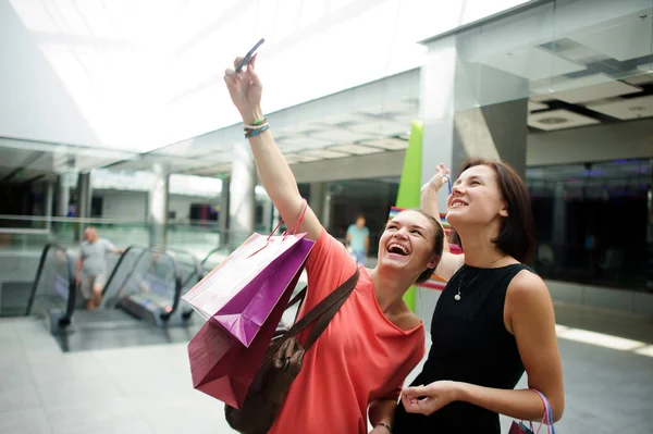 Two cute girlfriends make selfie at the Mall.