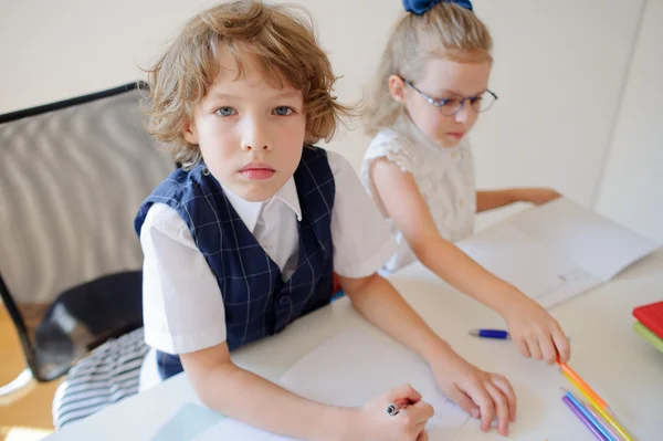 Two small disciples of an elementary school sit at a desk.