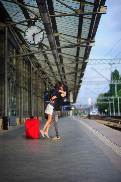 Couple stands on the empty platform under the clock.