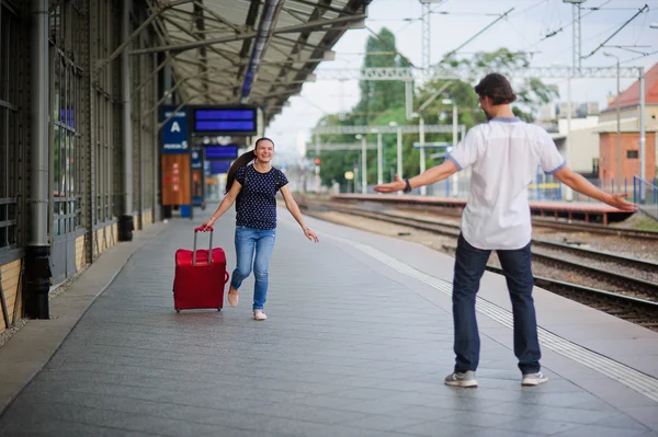 At an empty platform flee a young woman with red suitcase.