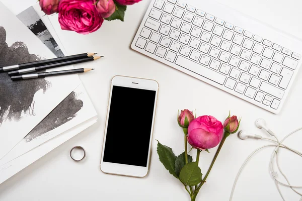 Smartphone, computer keyboard and fesh pink flowers on white tab