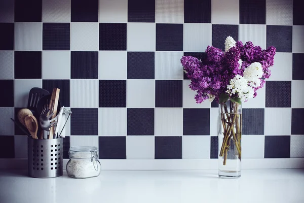 Lilacs in a vase and kitchen utensils