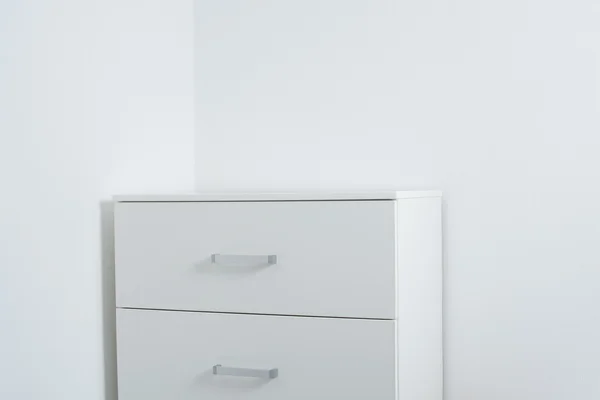 White wall and a chest of drawers