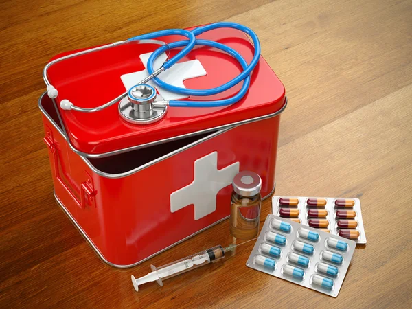 First aid kit with stethoscope, pills and syringe on the table.