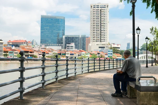 Man Sitting on a Public Bench with a View of Urban Singapore