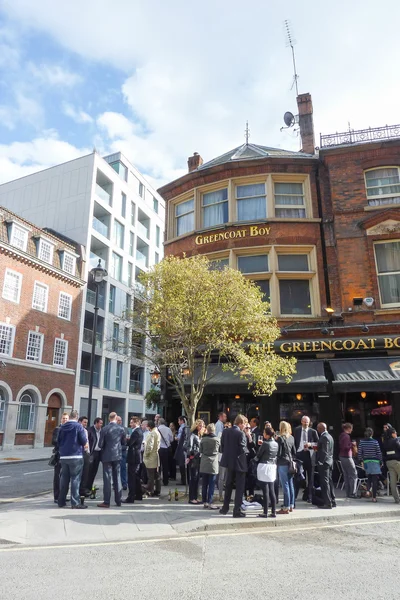 People drinking in front of a typical pub in the London city center.