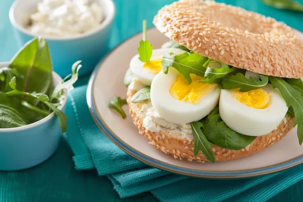Breakfast sandwich on bagel with egg cream cheese arugula
