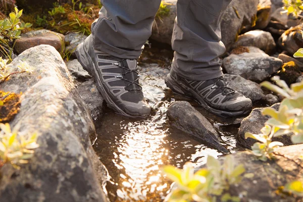 Hiker crossing a river. legs in boots