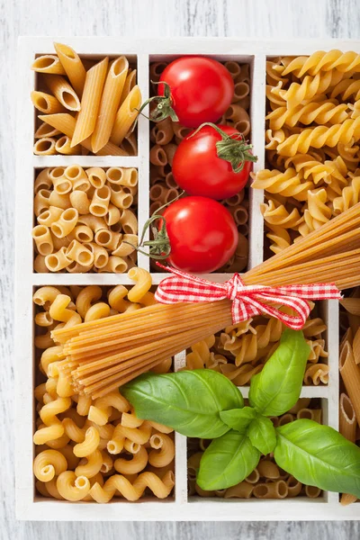 Various raw wholegrain pasta in white wooden box