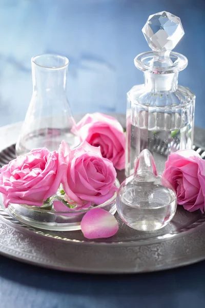 Alchemy and aromatherapy with rose flowers and chemical flasks