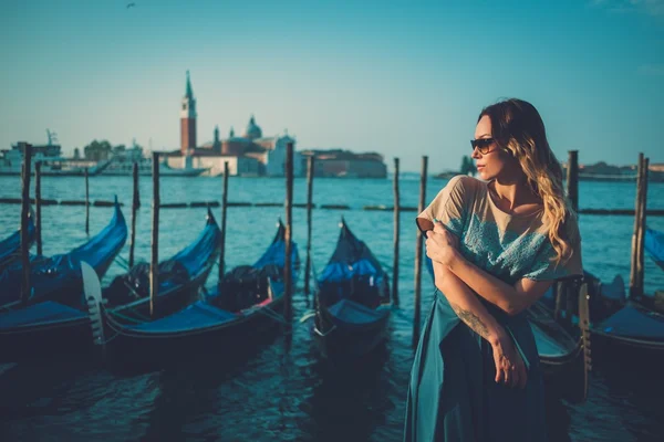 Beautiful well-dressed woman standing near San Marco square with gondolas and Santa Lucia island on the background.