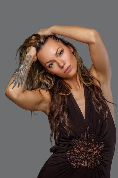 Woman in a brown dress with tattoo on her hand