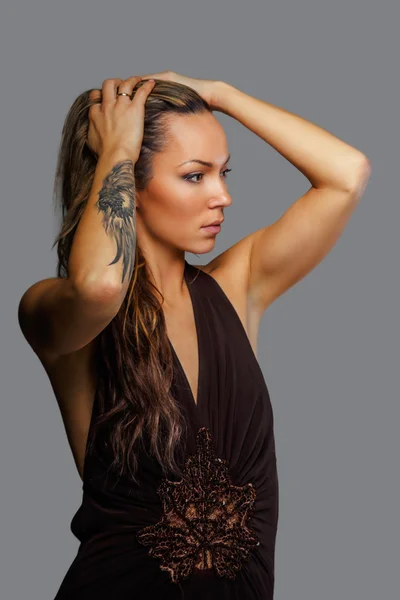 Woman in a brown dress with tattoo on her hand