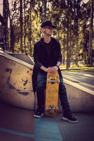 Man in black clothes posing with skateboard