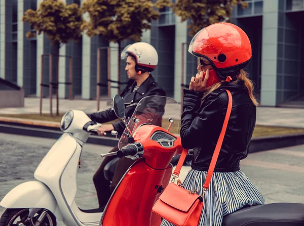 Male and female on motor scooters