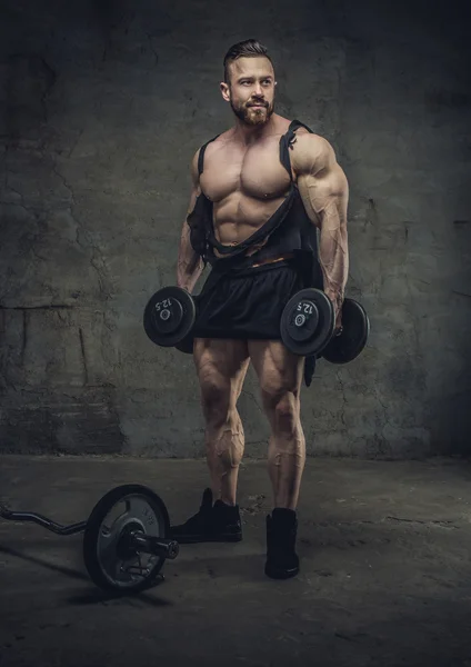 Bodybuilder with dumbbells in a studio