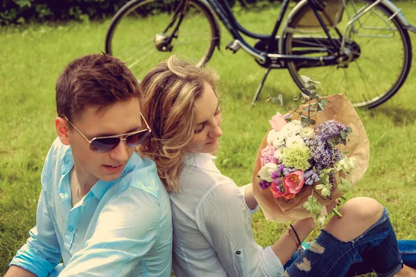 Blond female with flowers and male in sunglasses