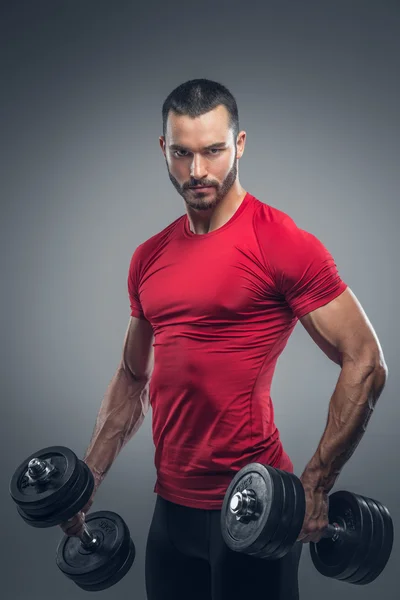 Male in a red t shirt holds dumbbells