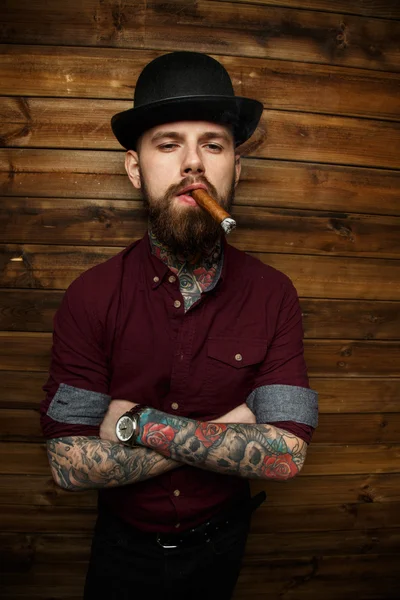 Male with tattoo smokes cigar