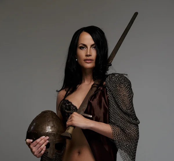 Goregeous female warrior poses holding sword and helmet