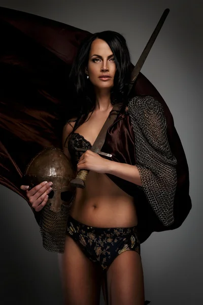 Goregeous female warrior poses holding sword and helmet