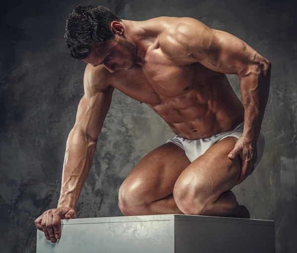 Bodybuilder  posing on white podium