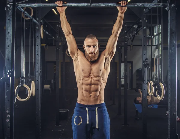 Shirtless muscular man in blue sports pants.