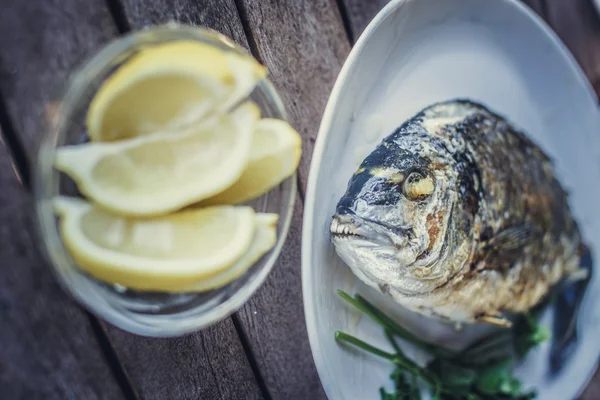 Fish food on white plate with lemon.