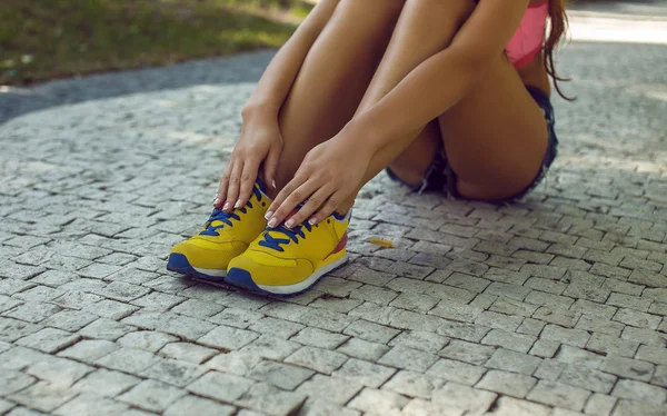 Woman's legs in yellow sports shoes on grey surface.