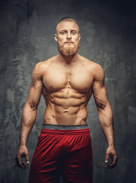 Shirtless muscular bearded man in red pants.