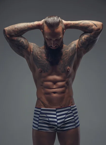 Tattooed bearded man in stripes panties.