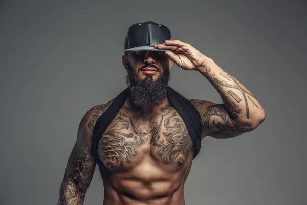 Brutal tattooed man in black cap.