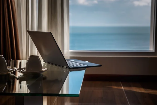 Thin laptop on glass table.