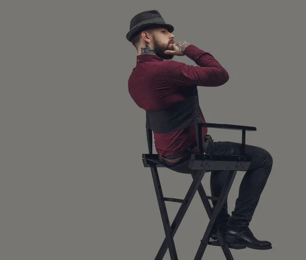 Man in hat sitting on chair.