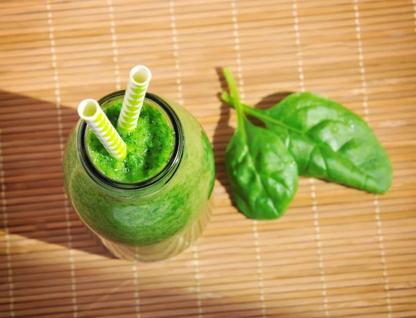 Green spinach smoothie in jar with straws. Healthy breakfast concept. Top view