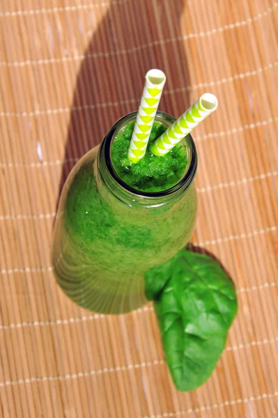 Green spinach smoothie in jar with straws. Healthy breakfast concept. Top view