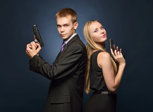 Beautiful spy couple in evening dress with a guns.