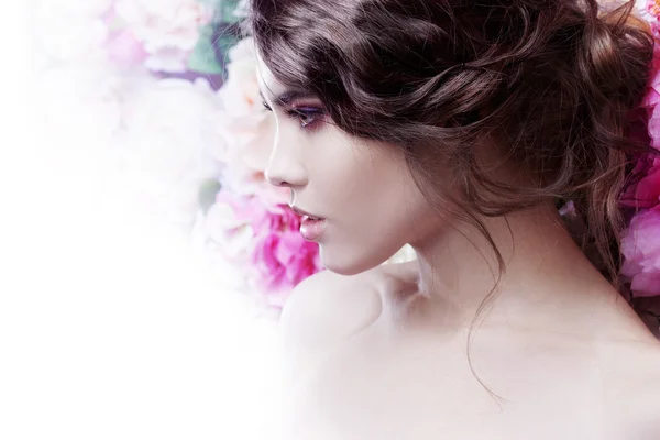 Profile of  beautiful fashion girl, sweet, sensual. Beautiful makeup and messy romantic hairstyle. Flowers background.