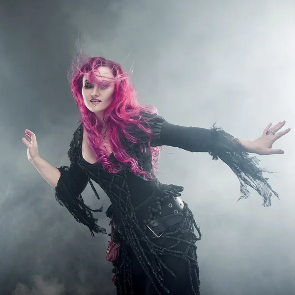 Halloween Witch creates magic. Attractive woman with red hair in witches costume