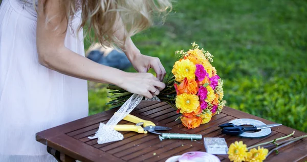 Young beautiful woman florist. The girl in the Park draws a bouquet. Outdoor