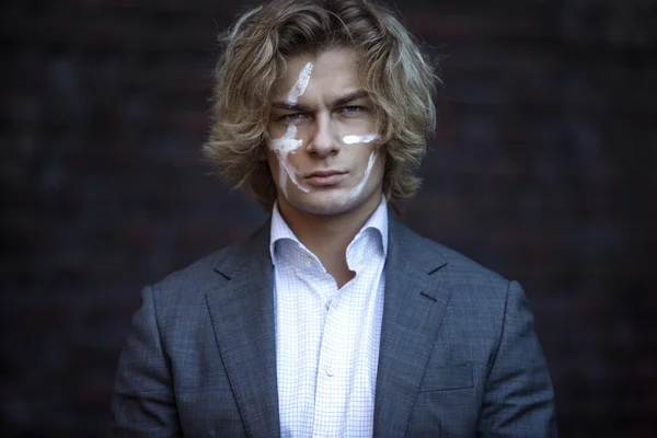 Businessman warrior. Young man makes war paint on his face, concept