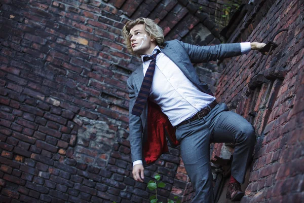 Businessman warrior. Young man  with  war paint on his face climbs up the wall , concept