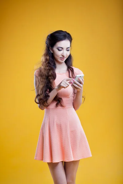 Fashion asian young  girl with mobile phone. Portrait on yellow background