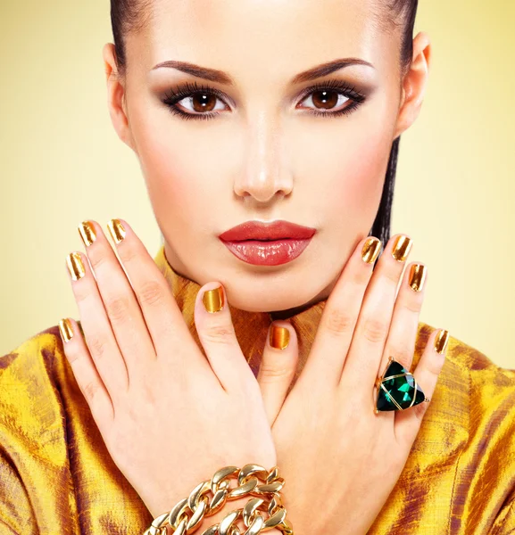 Woman with  golden nails and emerald ring